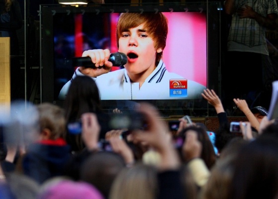 Fãs assistem performance do cantor Justin Bieber por um telão em Sydney, na Austrália (26/4/2010). O show, que seria do lado externo, teve de ser cancelado após mais de 5 mil pessoas acamparem desde o dia anterior, e diversas jovens se machucarem no meio da multidão