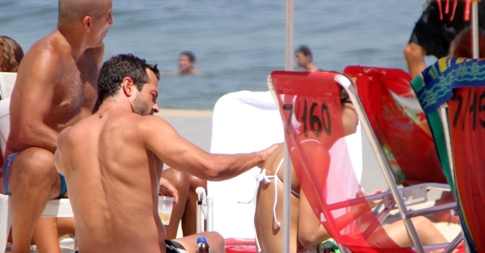 Após anunciar o fim do namoro, Malvino Salvador passa protetor nas costas de Sophie Charlotte na praia da Barra da Tijuca, no Rio de Janeiro. Eri Johnson também estava com o casal (8/2/12)