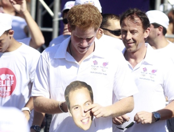 O príncipe Harry ganha uma máscara com a cara do seu irmão, o príncipe William, durante a corrida beneficente (10/3/12)