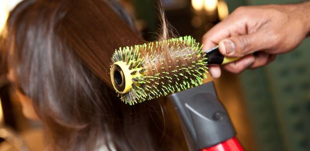 Cabeleireiro seca o cabelo com secador de cabelo para uma mulher após um  corte de cabelo no salão