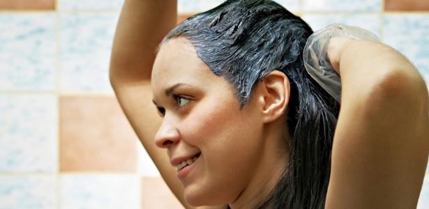 Cabeleireiro divide o cabelo feminino em seções com o pente segurando o  cabelo com as mãos em salão de cabeleireiro close-up.