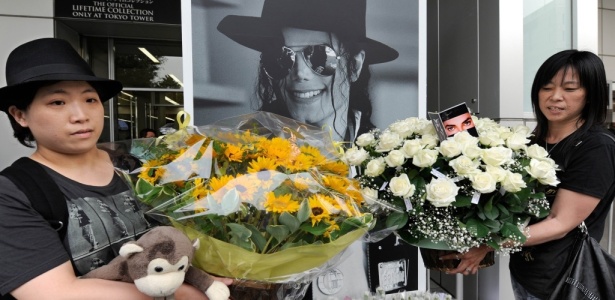 Fãs seguram flores em frente a cartaz com imagem de Michael Jackson em Tóquio (25/06/2010) - AFP PHOTO/Toru YAMANAKA