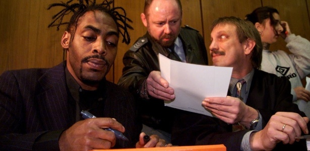 O rapper norte-americano Coolio (à esq.) dá autógrafo para policial alemão enquanto espera julgamento em Boeblingen, na Alemanha (26/11/98). Ele foi acusado de envolvimento em roubo e agressão. - Kai Pfaffenbach/REUTERS
